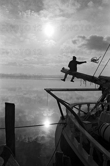 Sailor Sitting on Pole on Sailboat