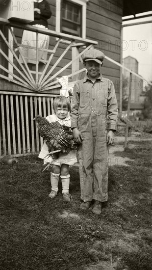 Young Boy Standing Next to Young Girl Holding Chicken