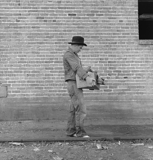 Cotton Picker Carrying Farm Security Administration (FSA) Grant of Food and Necessities to to his Family at FSA Migrant Camp, Bakersfield, California, USA, Dorothea Lange for Farm Security Administration, November 1938