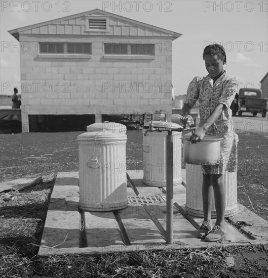 Young Girl Filling Pot with Water, Okeechobee Migratory Labor Camp, Belle Glade, Florida, USA, Marion Post Wolcott for Farm Security Administration, June 1940
