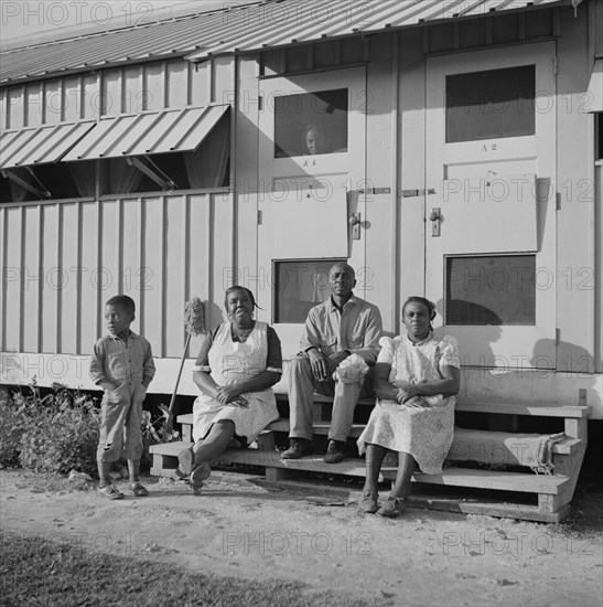 Family of Migratory Laborers Sitting in front of their Metal Shelter, Okeechobee Migratory Labor Camp, Belle Glade, Florida, USA, Marion Post Wolcott for Farm Security Administration, February 1941