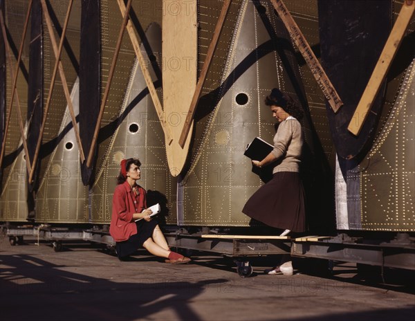 Female Inspectors, One Seated and One Standing, Making Notes while Checking Cargo Transport Inner Wings before Assembly on Fuselage, Douglas Aircraft Company, Long Beach, California, USA, Alfred T. Palmer for Office of War Information, October 1942