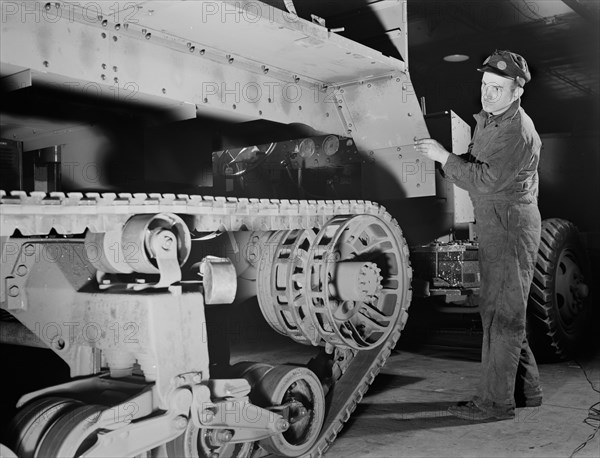 Worker Lowering Partly-finished Halftrac Scout Car Body on Chassis at War Plant that Formerly Produced Locks and Safes, Diebold Safe and Lock Company, Canton, Ohio, USA, Alfred T. Palmer for Office of War Information, December 1941