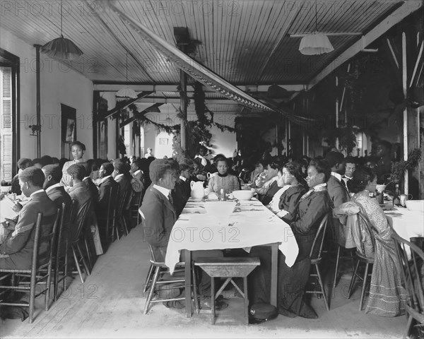 Male and Female Students Sitting at Tables in Dining Hall Decorated for the Holidays, Tuskegee Institute, Tuskegee, Alabama, USA, by Frances Benjamin Johnson, 1902
