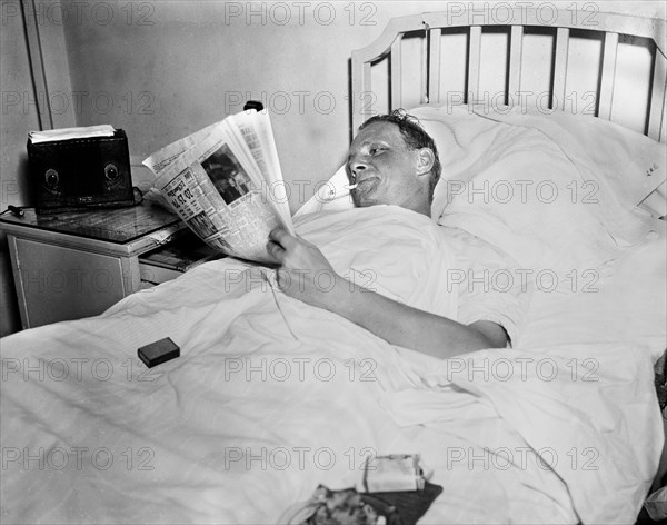 Man Smoking Cigarette while Reading Newspaper in Hospital Bed, Harris & Ewing, 1936