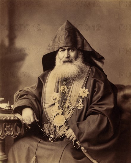 Armenian Patriarch of Jerusalem, Harootiun Vehabedian, Seated Portrait Wearing Hooded Vestment, Adorned with Crosses and other Medals, Holding a Strand of Beads, Jerusalem, American Colony Photo Department, early 1900's