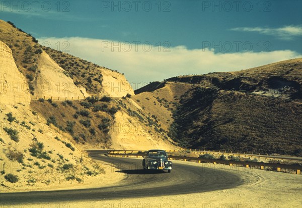 Car Traveling on Road Cut into Barren Hills Leading into Emmett, Idaho, USA, Russell Lee for Farm Security Administration - Office of War Information, July 1941