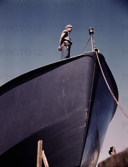 Coast Guard Sentry Standing Watch over New Torpedo Boat Under Constructions at Shipyard, Higgins Industries, Inc., New Orleans, Louisiana, USA, Howard R. Hollem for Office of War Information, July 1942