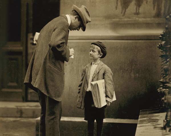 Michael McNelis, 8-year-old Newsboy, just recovering from Pneumonia, found Selling Papers in Rain Storm at time of photo, Portrait with Adult Man, Philadelphia, Pennsylvania, USA, Lewis Hine for National Child Labor Committee, June 1910