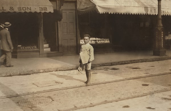John Sims, 7 years, Newsie, Portrait Standing on Street, New Bedford, Massachusetts, USA, Lewis Hine for National Child Labor Committee, August 22, 1911