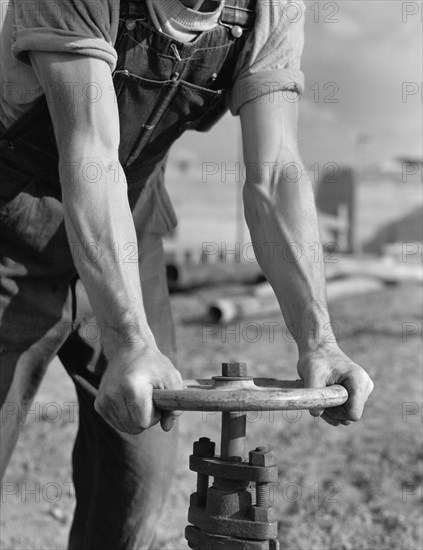 Construction Worker Opening Valve on new Pipeline of Fort Loudon Dam being built by Tennessee Valley Authority, Loudon County, Tennessee, USA, Alfred T. Palmer for Office of War Information, June 1942