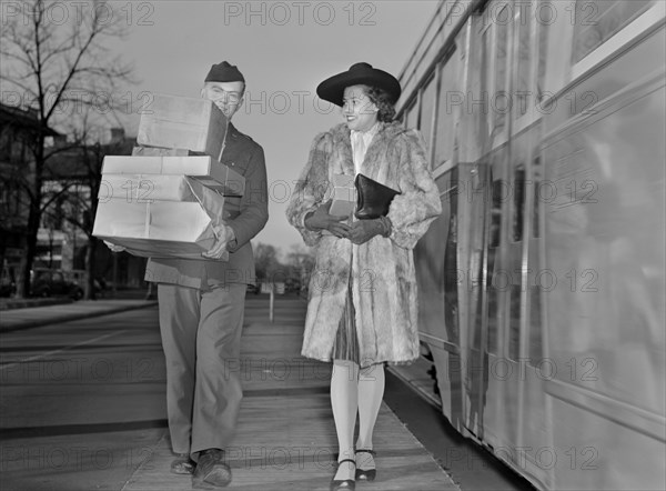 Military Man Carrying Packages and Escorting Woman to her Home from Bus Stop now that Delivery of Goods have been Curtailed to Conserve on Tires and Gasoline during World War II, Ann Rosener for Office of War Information, December 1942