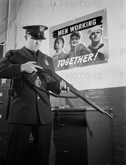 Sentinel Inspecting Rifle as he Keeps Vigil Against Saboteurs at Factory Converted to War Production, White Motor Company, Cleveland, Ohio, USA, Alfred T. Palmer for Office of War Information, December 1941