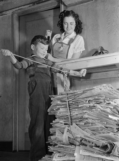 Mother Watching Young Son Tie up Large Bundle of Newspapers, as Conservation of Waste Paper will Save Millions of Dollars Annually for Uncle Sam during War Effort, Ann Rosener, Office of War Information, February 1942