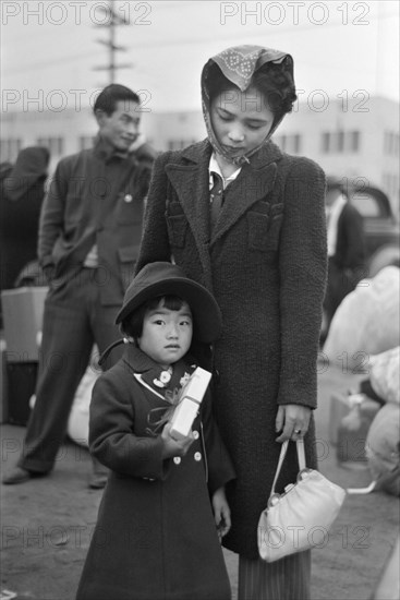 Japanese-American Mother and Daughter Waiting for Train to Owens Valley During Evacuation of Japanese-Americans from West Coast Areas under U.S. Army War Emergency Order, Los Angeles, California, USA, Russell Lee, Office of War Information, April 1942