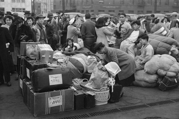 Japanese-Americans with Baggage Waiting for Train to Owens Valley During Evacuation of Japanese-Americans from West Coast Areas under U.S. Army War Emergency Order, Los Angeles, California, USA, Russell Lee, Office of War Information, April 1942
