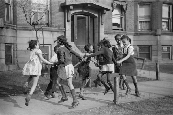 Group of Girls Playing Ring-Around-a-Rosie on Sidewalk in "Black Belt" Neighborhood, Chicago, Illinois, USA, Edwin Rosskam for Office of War Information, April 1941