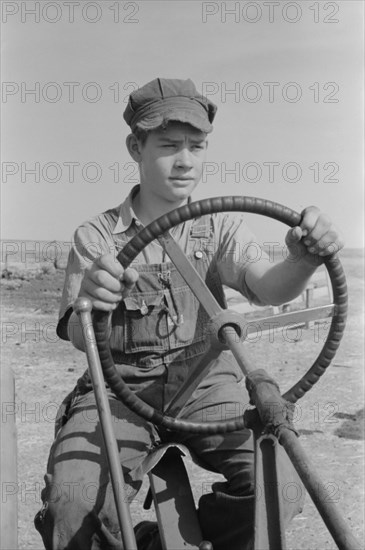 Son of Mr. Germeroth, FSA Client, Portrait Sitting at Steering Wheel of Tractor, Sheridan County, Kansas, USA, Russell Lee, Farm Security Administration, August 1939