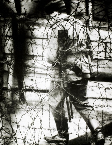 East German Border Guard Viewed Through Barbed Wire Fence, 1965