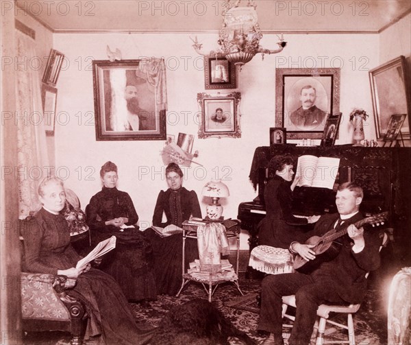 Family Sitting in Parlor While One Person Plays Piano and One Plays Guitar, USA, circa 1890