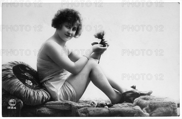 French Lingerie Model Seated on Chaise Lounge Holding Flower, circa 1920