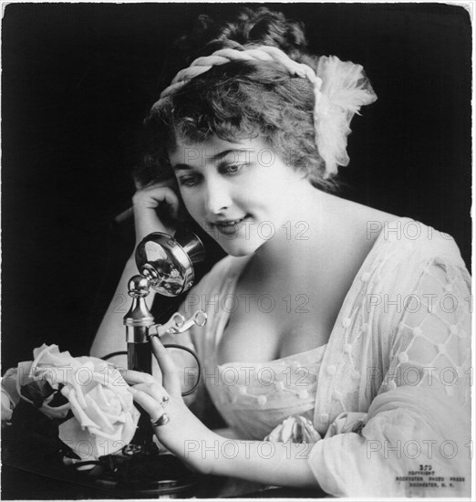 Woman Sitting at Table Holding Telephone, Postcard, circa 1910