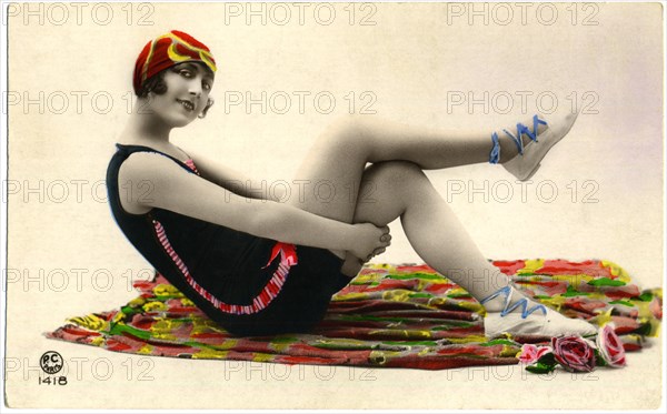 Seated Woman on Colorful Blanket Wearing Dark Swimsuit and Red Cap, Holding Thighs, Hand-Colored, French Postcard, circa early 1900's