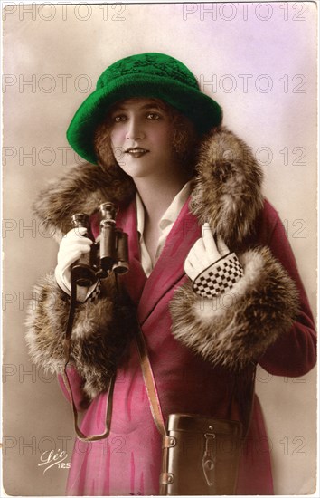 Fashionable Woman in Fur-Trimmed Coat and Green Hat Holding Binoculars, Hand-Colored Postcard, France, circa 1922