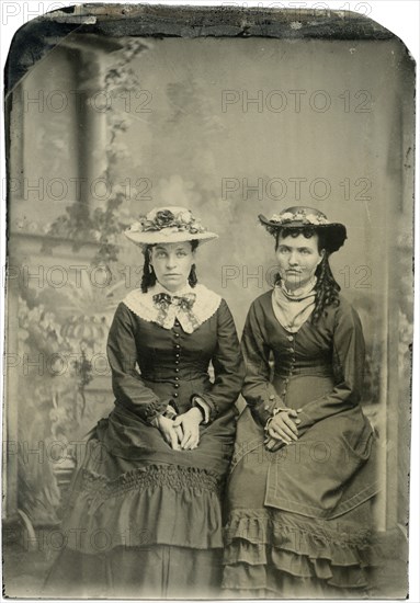 Portrait of Two Adult Women in Hats and Long Dresses, Both Seated with Hands Folded, Studio Shot, circa 1870