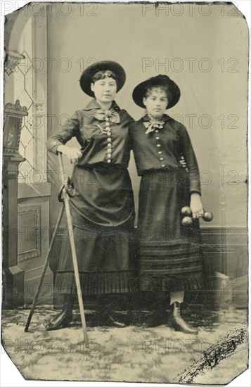 Portrait of Two Young Adult Women, Both Standing in Hats and Long Skirts with Poles, Rings and Weights, circa 1870