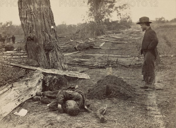 Man Looking at Grave of 1st Lt. John A. Clark, Company D, 7th Michigan Infantry, as Dead Rebel Soldier lies Nearby, Battle of Antietam, Antietam, Maryland, USA, Alexander Gardner, September 19, 1862