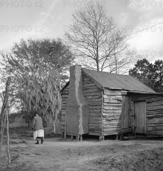 Woman Walking in Yard by Rural Cabin, near Beaufort, South Carolina, USA, Marion Post Wolcott, Farm Security Administration, December 1938