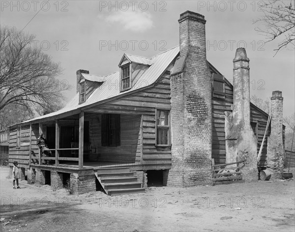 Man Sitting on Porch of Wood House while Young Girl Stands in Front Yard, Georgetown, South Carolina, USA, Frances Benjamin Johnston, 1937