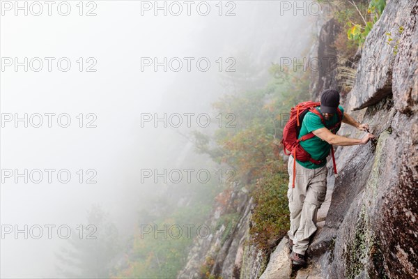 Man Hiking on Cliff on Foggy Day, Acadia National Park, Maine, USA