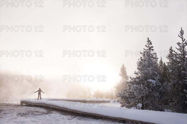 Man Raising Arms in Snowy Landscape at Sunrise