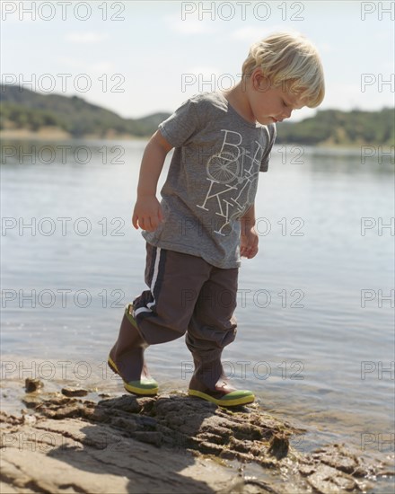 Young Boy Walking Along Edge of Lake