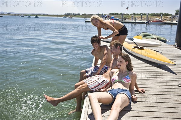 Two Young Couples Sitting on Edge of Pier