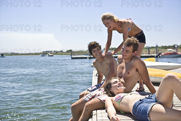 Two Smiling Young Couples Sitting on Edge of Pier