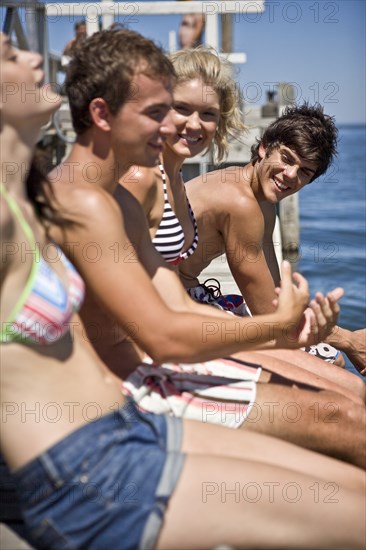 Two Smiling Young Couples Sitting on Edge of Pier