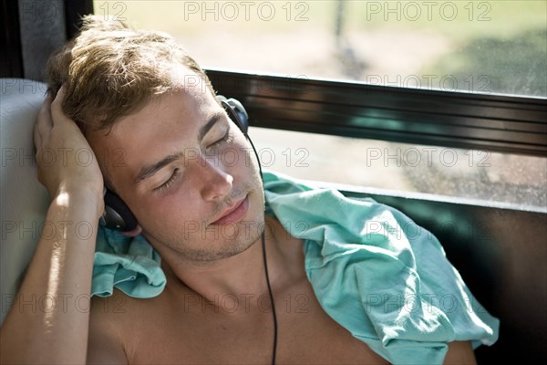 Young Man With Headphones Sleeping on Bus