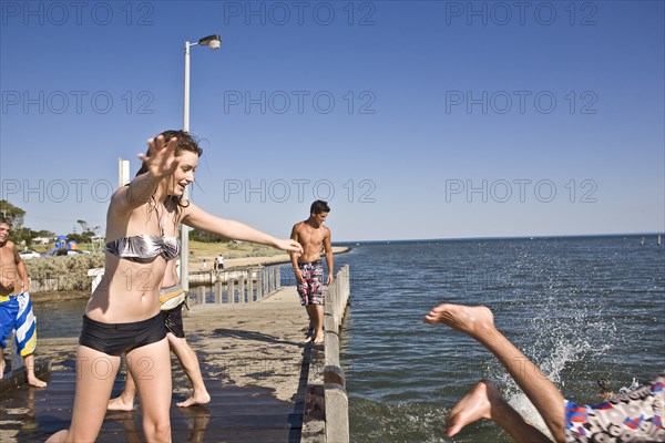 Young Woman Pushing Young Man into Water