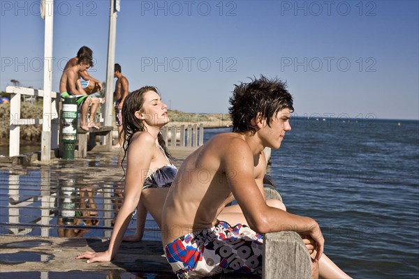 Young Couple Sitting on Edge of Pier