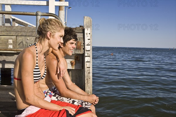 Young Couple Sitting on Edge of Pier