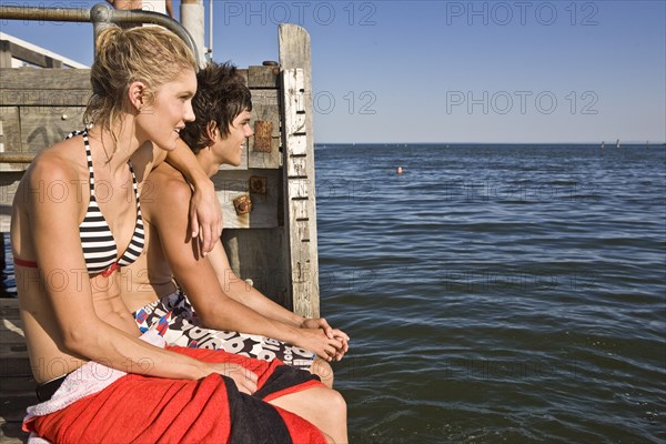 Young Couple Sitting on Edge of Pier