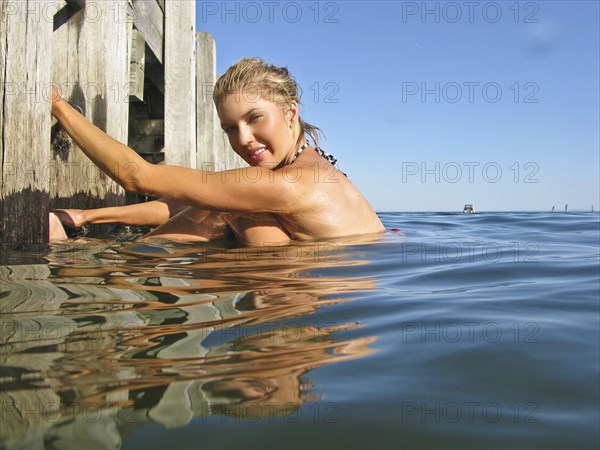 Young Woman in Water Holding on to Pier Steps, Portrait