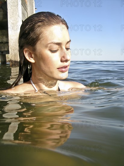 Young Woman in Water Near Pier, Portrait