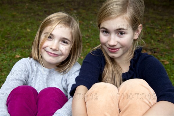 Two Smiling Girls With Arms Wrapped Around Legs