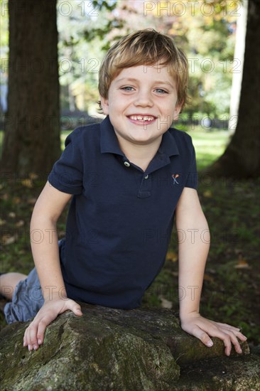 Smiling Blonde Boy Leaning on Rock