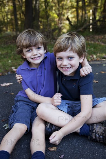 Two Young Boys Hugging Each Other on Pavement