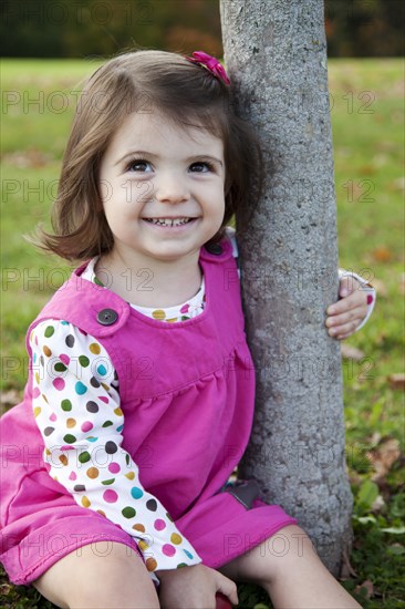 Young Girl Sitting Next to Tree